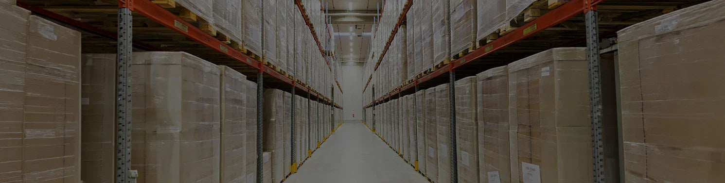 Long aisle in a warehouse with rows of stacked cardboard boxes.